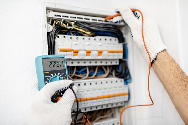 Electrician checking voltage of switchboard